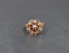A 9ct gold garnet and seed pearl cluster ring in an open frilled mount, damage to pearl and loop