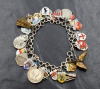 A white metal charm bracelet marked 835S, having a collection of white metal charms, mostly souvenir