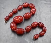 A graduated red bead necklace presumed to be cherry amber, the largest bead measuring