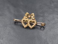 A yellow metal seed pearl double heart brooch, the twinned heart motif set with seed pearls, and