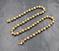 A yellow metal beaded necklace, the alternating smooth and textured beads tests as between 18-