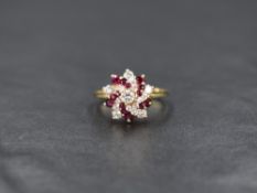 An 18ct gold diamond and ruby swirl cluster ring having a stepped claw set mount on an 18ct gold