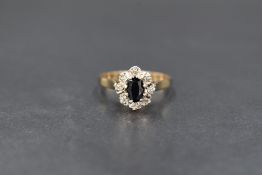An 18ct gold sapphire cluster ring, the central oval cut blue sapphire in an illusion set diamond