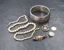 A silver hinged bangle, having engraved floral decoration and 'MW' initials, along with a silver