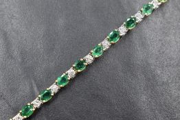 An 18ct gold emerald and diamond tennis bracelet, the twenty oval cut emeralds interspersed with