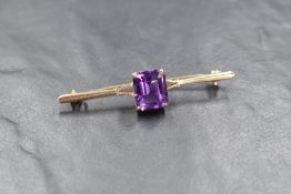 A 9ct gold amethyst bar brooch, having an emerald cut amethyst to the centre with split shoulders,
