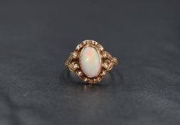 An opal ring having an oval cabochon stone in a collared decorative mount on rose gold loop, no