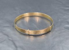 A 9ct gold expanding bangle, having decorative scroll engraving, 7.8g