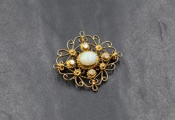 A yellow metal brooch having a central opal cabouchon within a four stone diamond surround in an