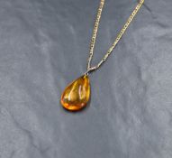 A large teardrop amber pendant, having a silver pin attachment on a 9ct gold curb link chain, 12g