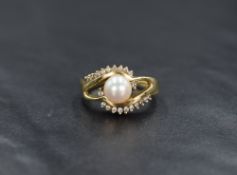A 14ct gold cultured pearl and diamond ring, the central pinkish white lustre pearl in a twisted