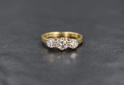 An 18ct gold diamond trilogy ring, the central round brilliant cut diamond measuring approximately