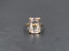 A 9ct gold quartz ring, the emerald cut quartz having a very pale purple tint, in a four claw