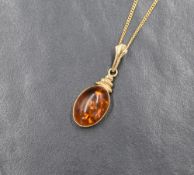 A 9ct gold amber pendant, the oval bezel set amber with a decorative articulated mount, on an 18ct