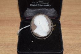 A conch shell cameo brooch depicting a gentleman in profile in a collared white metal mount, no