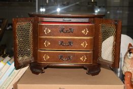 A wooden musical jewellery box, having decorative engraving to the top, with pierced doors and three