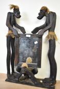 A vintage Asmat Tiki table top mirror supported either side with carved wooden tribal figures having