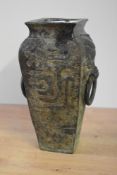 A heavy Chinese bronze vase of tapering square form having archaic mythical creatures over Greek key