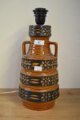 A vintage West German pottery two handled lamp, decorated having flower patterns on a burnt orange