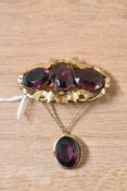 An impressive yellow metal and paste brooch, the three central oval cut purple paste with a