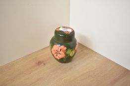 A Moorcroft pottery Hibiscus pattern lidded ginger jar, decorated with a green glazed ground,