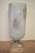 A large contemporary studio style marble effect glass vase, supported on a rectangle chrome base,