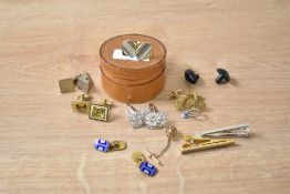 A circular leather lidded stud pouch containing various men's cufflinks and tie clips, w6.5cm