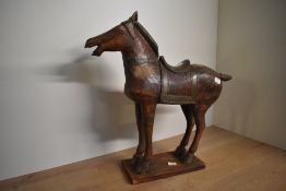 A large Chinese Tang-style wooden horse sculpture, stood on all fours having brass saddle and drape,