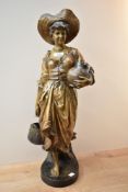 A reproduction Goldschieder figure depicting a female carrying water, markings to backside measuring