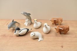 A group of eight Scottish porcelain animal studies comprising seal pup, highland cows, dolphins
