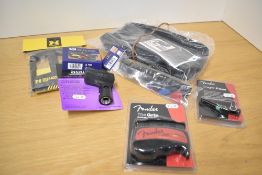 A bundle of accessories including guitar maintenance kit, Fender capo and grip aid, hercules cradle,
