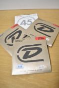 Four sets of bass guitar strings (3 x Dunlop, 1 x Fender)