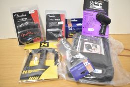A bundle of accessories including guitar maintenance kit, Fender capo and grip aid, hercules cradle,