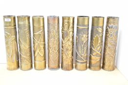A group of eight French World War I 75DEC brass Trench Art shell cases, seven decorated in relief