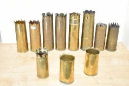 A selection of eleven various World War I brass Trench Art shell cases, each with shaped surmounts