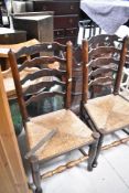 A pair of 19th Century elm or ash dining chairs having shaped ladder backs and rush seats