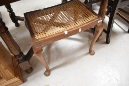 An early 20th Century stained frame Queen Anne style dressing table stool, having bergere canework