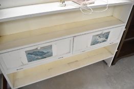 A vintage painted shallow bookshelf with flapped storage sections to centre shelf, width approx.