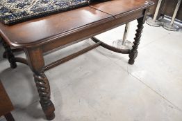 An early 20th Century oak dining table having H stretcher and twist legs supports, approx. 133 x