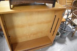 A vintage lightwood bookshelf with additional side door storage