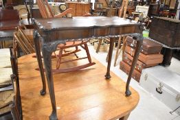 A Continental style mahogany occasional table having shaped top and leg with foliate detailing,