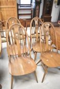 A set of four Ercol swan back dining chairs , having high backs and h stretcher , in mid stain