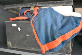 A vintage metal box holding a range of horse jackets, belts, straps, shoes ect