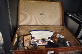 A vintage suitcase containing a variety of items including a wooden carved egg box, two Stratton