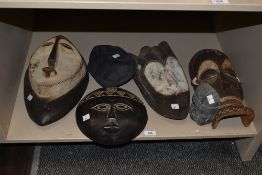 A group of vintage wooden African tribal masks in various shapes and sizes, the largest measuring