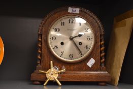An early 20th century oak cased 8-day mantel clock having barley twist columns and silvered dial