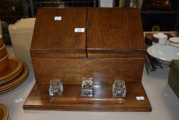 An early 20th century oak stationary cabinet having three inkwells, the front opens with two doors