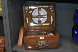 An early 20th century leather-cased picnic set for one, inside fitted with flask, salt, pepper,