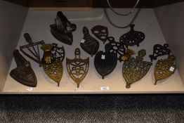 An assortment of brass iron trivets in various sizes and designs etc.