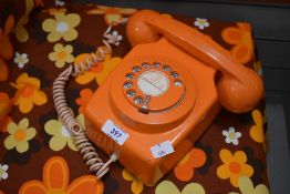 A retro orange telephone with rotary dial, D20cm